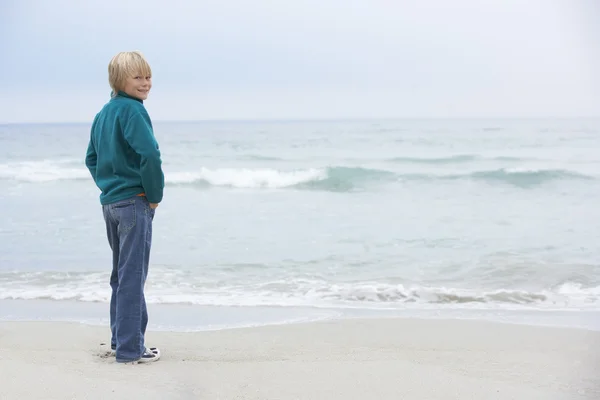 Jonge jongen op vakantie staande op winter strand uitzicht op zee — Stockfoto