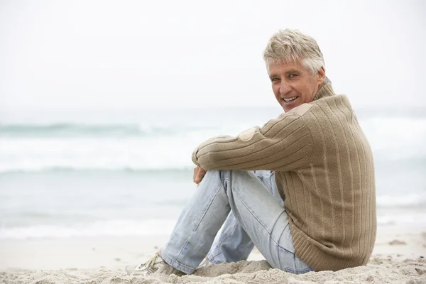 冬のビーチの上に座って休日シニア男性 — ストック写真