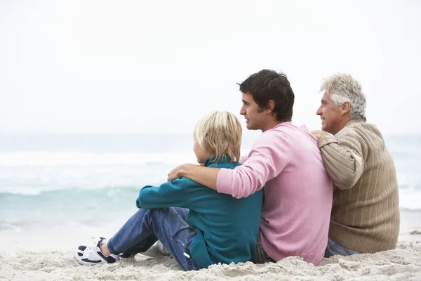Grootvader, vader en kleinzoon zittend op winter strand — Stockfoto