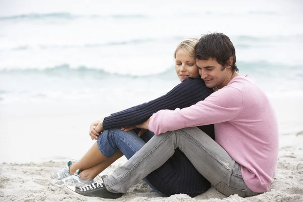 年轻夫妇坐在冬季海滩上的假期 — 图库照片