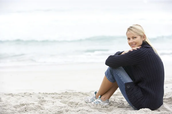 年轻的女子在坐在冬季海滩上的假期 — 图库照片