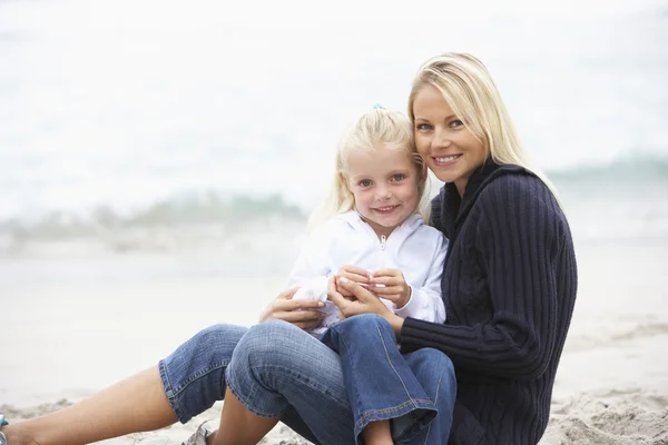 Madre e hija en vacaciones sentadas en la playa de invierno — Foto de Stock