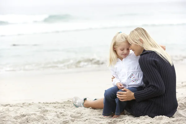 Mor och dotter på semester sitter på vintern beach — Stockfoto