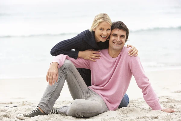 Молодая пара в отпуске, сидя на зимнем пляже — стоковое фото
