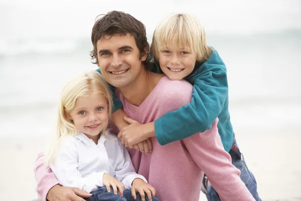 Otec i děti seděli na zimní beach — Stock fotografie