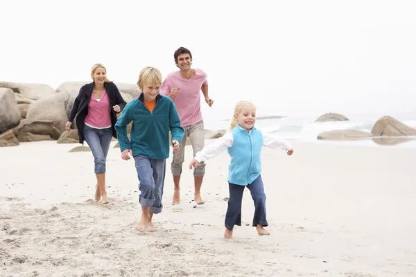 Familia joven corriendo a lo largo de la playa de invierno — Foto de Stock