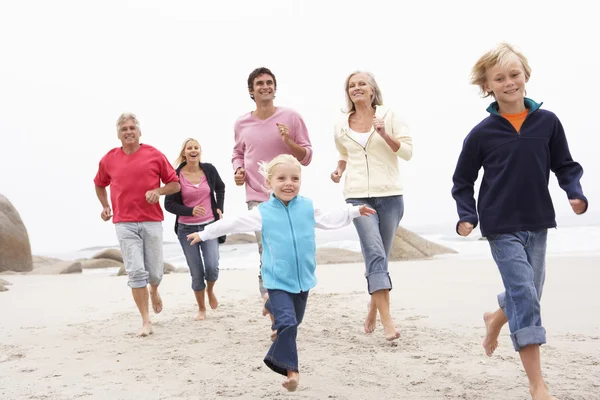 三代家庭一起沿着冬季海滩跑 — 图库照片