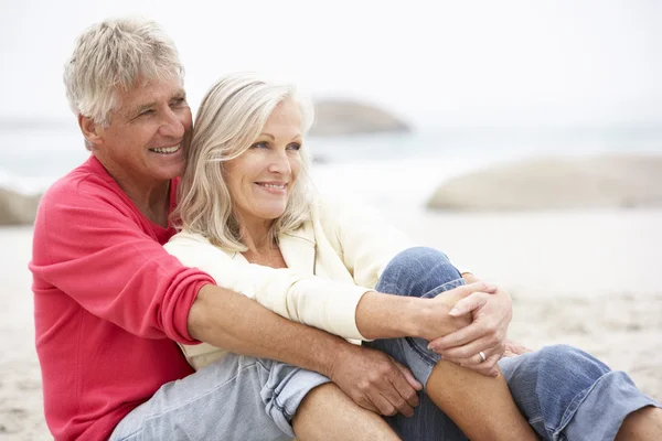 Seniorenpaar sitzt im Urlaub am Winterstrand — Stockfoto