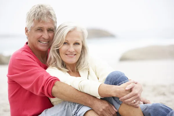冬のビーチの上に座って休日に年配のカップル — ストック写真