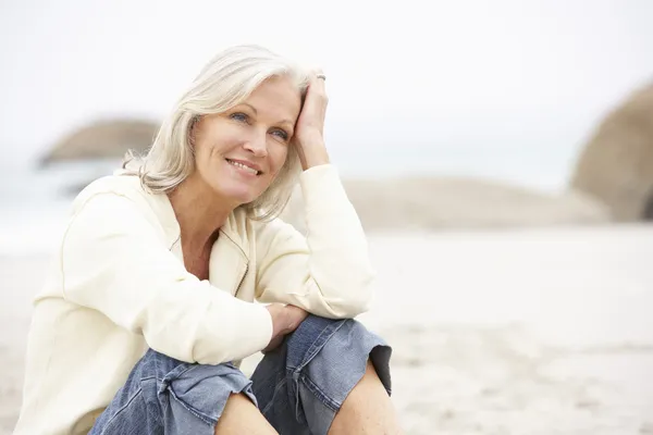 冬のビーチの上に座って休日に年配の女性 — ストック写真