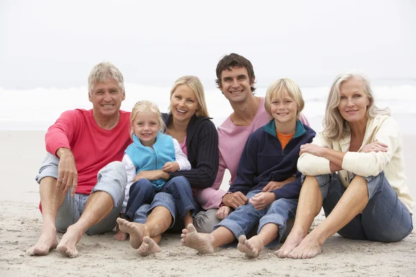 Familia de tres generaciones sentados en la playa de invierno juntos — Foto de Stock