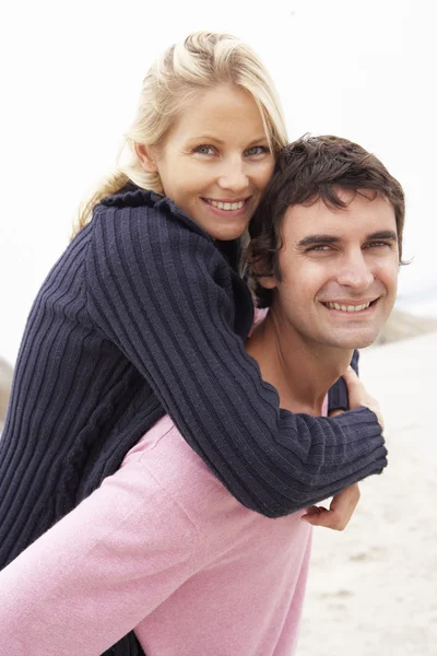 Homem dando mulher piggyback no inverno praia — Fotografia de Stock