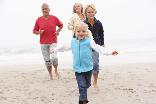 Abuelos y nietos corriendo juntos en la playa de invierno — Foto de Stock