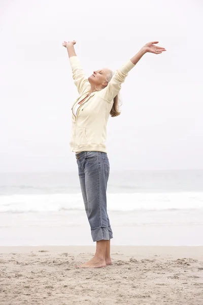 Mulher sênior com braços estendidos na praia de inverno — Fotografia de Stock