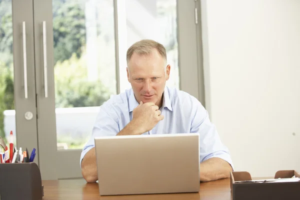 Людина середнього віку використовує ноутбук вдома — стокове фото