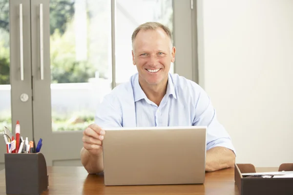 Людина середнього віку використовує ноутбук вдома — стокове фото