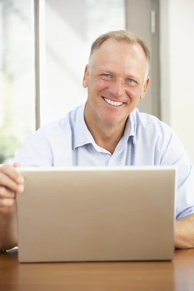 Uomo di mezza età che utilizza il computer portatile a casa — Foto Stock