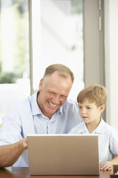 Отец и сын используют ноутбук дома — стоковое фото