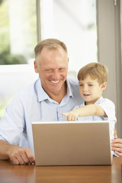 Far och son använder laptop hemma — Stockfoto