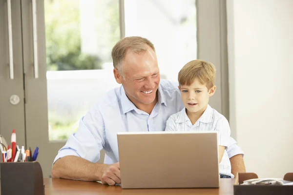 Pai e filho usando laptop em casa — Fotografia de Stock