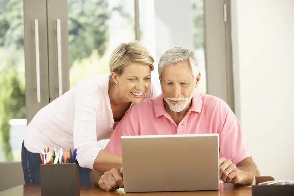 Fille adulte et père aîné utilisant un ordinateur portable à la maison — Photo