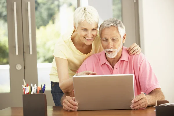 Пожилая пара с ноутбуком дома — стоковое фото