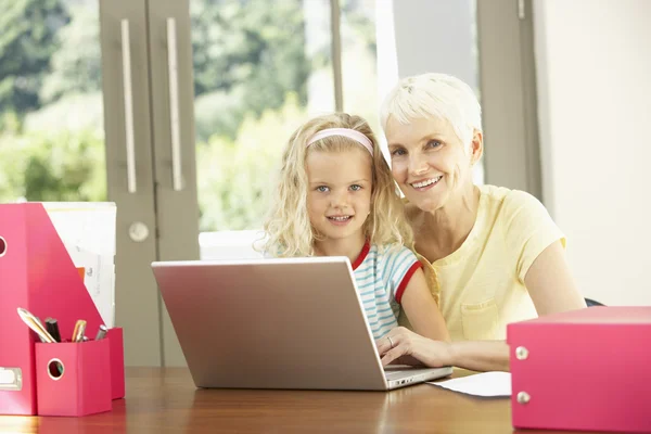 Vnučka a babička použití notebooku doma — Stock fotografie