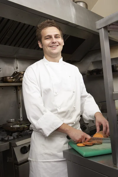 Männlicher Koch bereitet Gemüse in Restaurantküche zu Stockbild