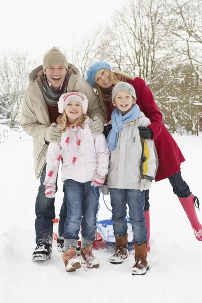 Family Pulling Sledge Through Snowy Landscape Stock Image