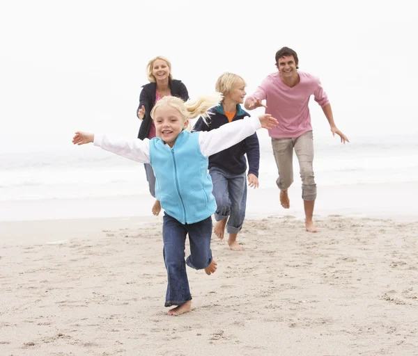 Young Family Running Along Winter Beach Stock Photo