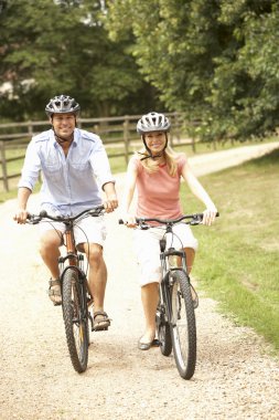 Couple Cycling In Countryside Wearing Safety Helmets clipart