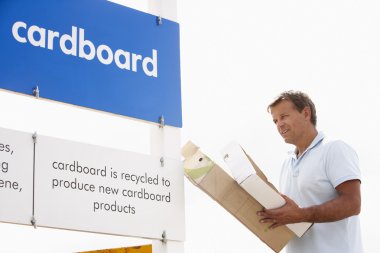 Man At Recycling Centre Disposing Of Cardboard clipart