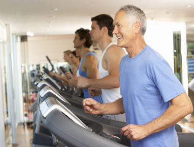 Senior Man On Running Machine In Gym clipart