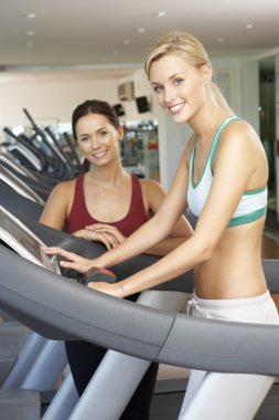 Woman Working With Female Personal Trainer On Running Machine In clipart