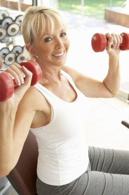 Senior Woman Working With Weights In Gym clipart