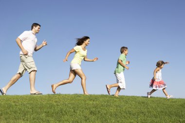 Young family, parents with children, running through field clipart