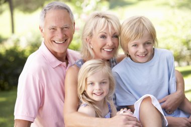 Senior couple with children posing in park clipart