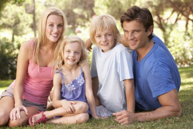 Young parents with children posing in a park clipart