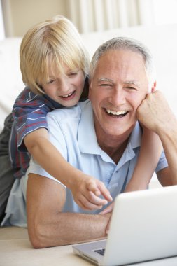 Senior man with young boy using laptop computer clipart