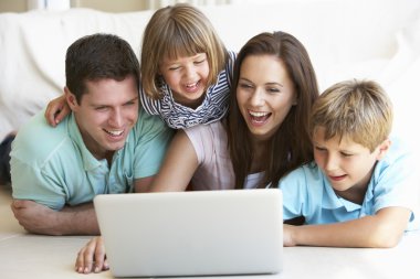 Young parents, with children, on laptop computer clipart