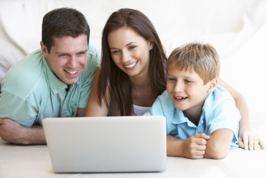 Young parents, with child, on laptop computer clipart