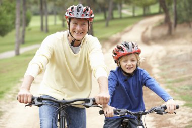 Grandfather and grandson riding bicycle in park clipart