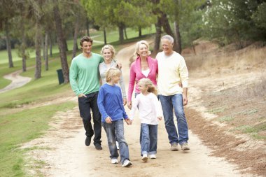 Three Generation Family enjoying walk in park clipart