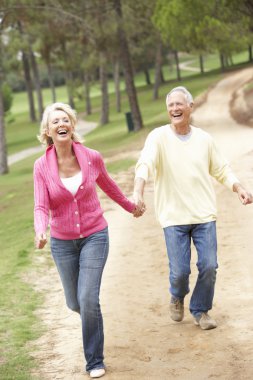 Senior Couple enjoying walk in park clipart