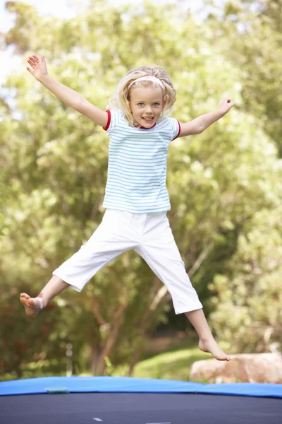 Jong meisje springen op de trampoline in tuin — Stockfoto