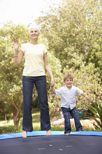 Бабушка и внук прыгают на батуте в саду — стоковое фото