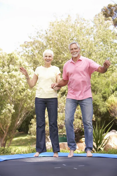 Seniorenpaar springt auf Trampolin im Garten — Stockfoto
