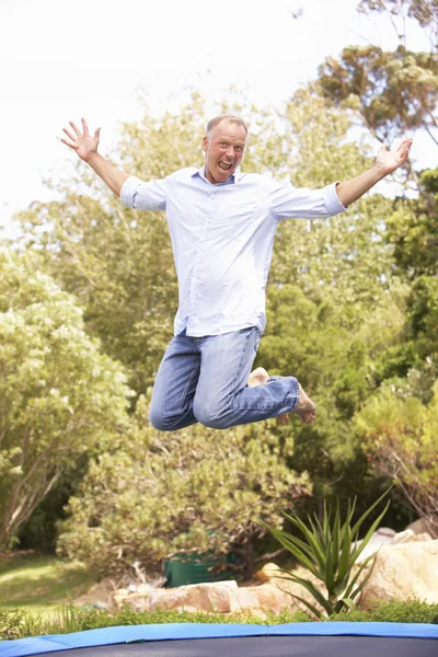 Homem de meia-idade pulando no trampolim no jardim — Fotografia de Stock