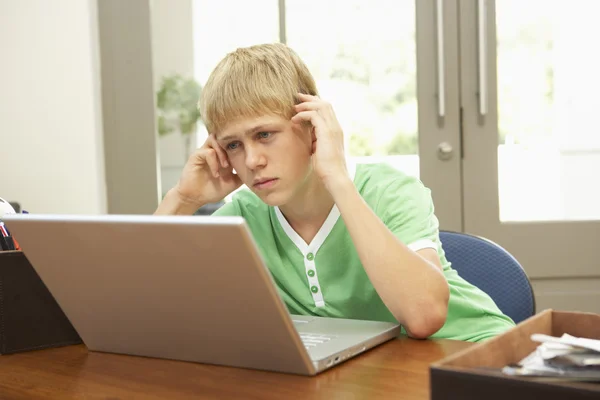 Sorgenvoll aussehender Teenager benutzt Laptop zu Hause — Stockfoto