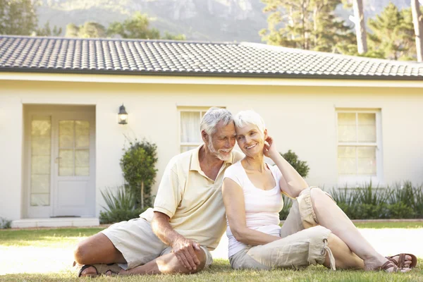 Seniorenpaar sitzt vor Traumhaus — Stockfoto